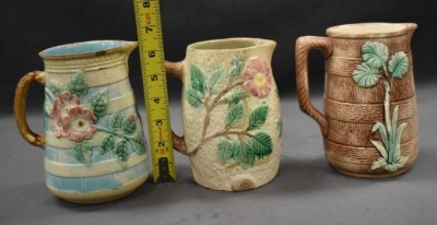 (3) Majolica 6" milk pitchers, all w/ plant or floral decorations - 12
