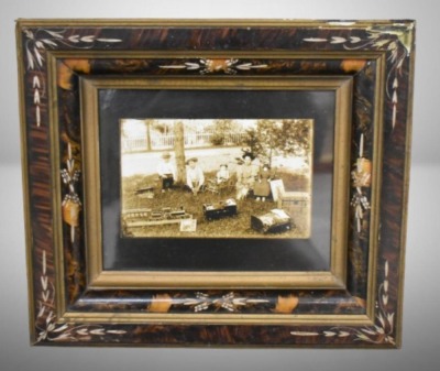 Framed photo of kids sitting outside with their toys, circa 1900