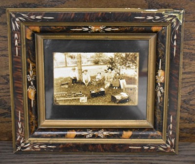 Framed photo of kids sitting outside with their toys, circa 1900 - 2
